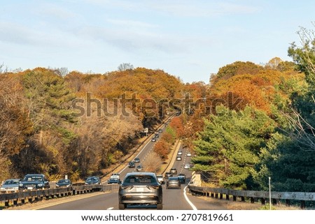 Drivers perspective over part of historic Merritt Parkway (CT-15) in Connecticut, USA that runs from Greenwich to Stratford busy with cars during autumn foliage