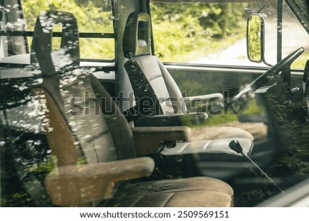 Drivers position of an old vintage van. Big plastic steering wheel and captain seats visible in a van from the 80s. View of steering wheel, controls, ignition lock and others