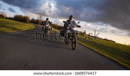 Drivers riding motorcycle on empty road during sunset, spring mountains