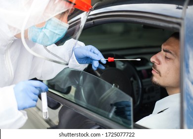 Drive-thru Coronavirus COVID-19 Test,paramedic In Personal Protective Equipment & Face Shield Performing Nasal Swab Through Car Window On Male Patient Sitting In Vehicle,mobile US Testing Site Center 