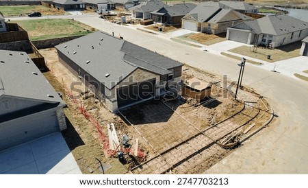 Driveway framing, rebar lined forms, yard prep construction progress shaping lot at corner home near Arabian Ln, Highpointe Ranch by US 377, Blackjack Rd. Dark shingles, brick texture, Aubrey, TX. USA