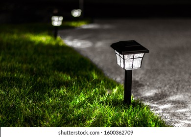 Driveway Lights In The Grass Illuminate The Edges Of A Driveway At Night.