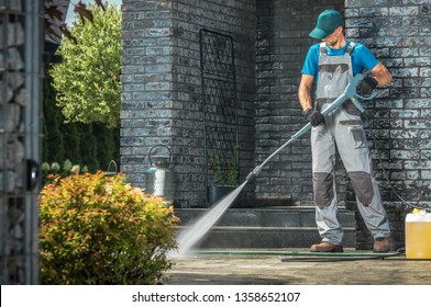 Driveway Pressure Washing. Caucasian Worker Cleaning Area in Front of the House.