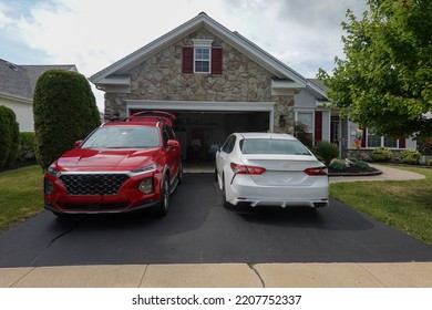 Driveway view of the stone facade of a house with two cars facing in different directions