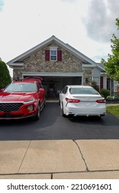 Driveway View Of The Stone Facade Of A House With Two Cars Facing In Different Directions