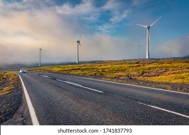 Driving among the field of wind turbines. Foggy summer scene of Faroe Islands, Denmark, Europe. Ecology concept background. 