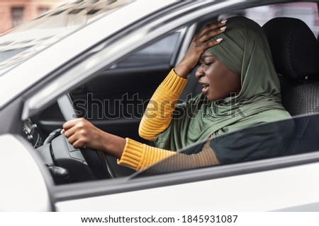 Driving Anxiety. Stressed Black Muslim Lady In Hijab Having Car Accident, African Islamic Lady Suffering Strong Headache While Drives Vehicle, Touching Head, Feeling Angry, Side View Shot