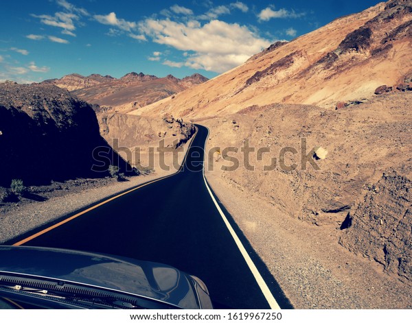 Driving around the Death Valley in sunny day\
seen from car hood\
perspective
