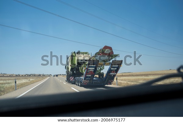 Driving behind heavy-duty\
truck carrying harvester. Heavy duty transports. View from the\
inside of the car
