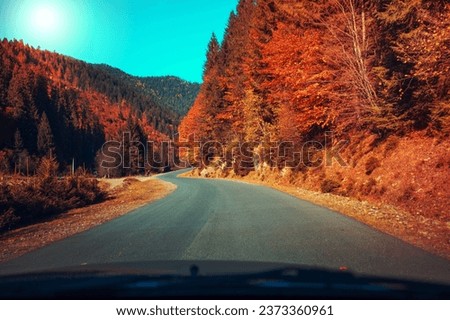 Driving a car along a mountain winding road. Empty road. View from a car to the autumn mountain landscape