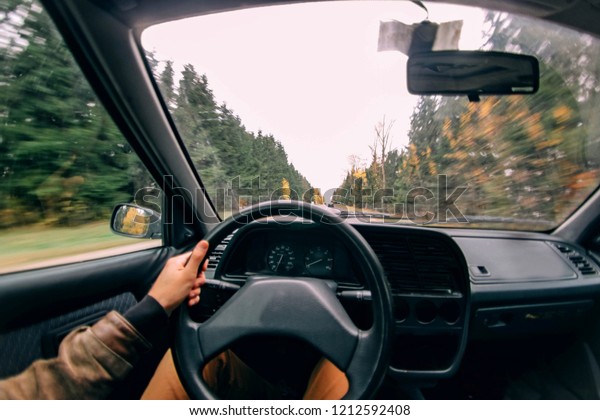 driving a car along a winding forest\
road in autumn. steering wheel, extreme\
driving.