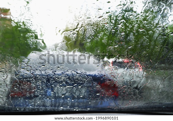 Driving a\
car in bad weather. Driving in a car in heavy rain. Difficult\
visibility from a car through a wet\
windshield