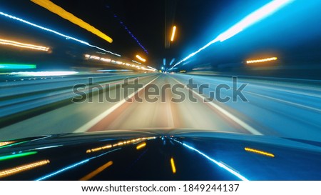 Driving a car in the city at night. The camera on the hood of the car. Hyperlapse in the evening in the center of the city on the highway. Abstract soft glowing lines.
