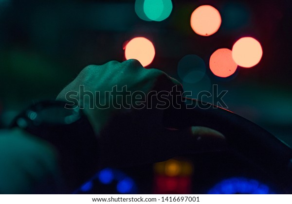 Driving a car at night -man driving his modern car\
at night in a city
