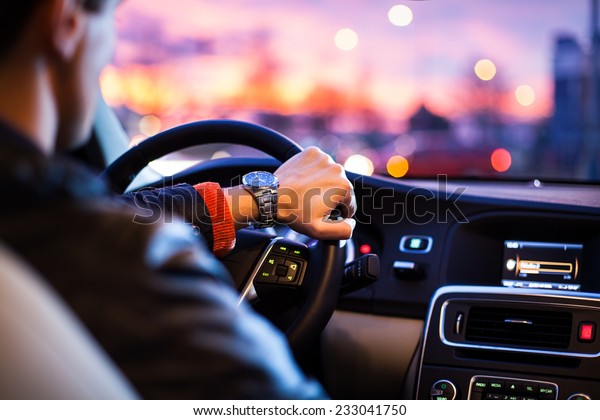 Driving a car at night\
-man driving his modern car at night in a city (shallow DOF; color\
toned image)