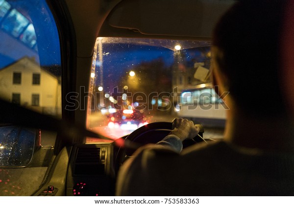 \
Driving a car at night, man\
driving his modern car at night in a city with lights out of the\
town