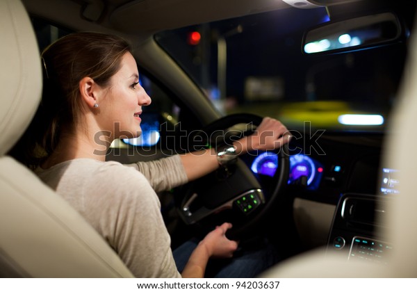 Driving\
a car at night - pretty, young woman driving her modern car at\
night in a city (shallow DOF; color toned\
image)