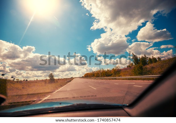 Driving a\
car on highway on a sunny day. Journey by car. View from car of\
road and beautiful cloudy sky. Ukraine,\
Europe