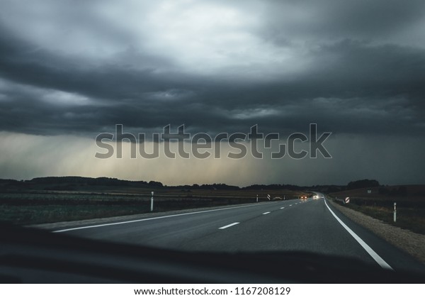 Driving in car on highway, view from car on \
storm weather in countryside. Rain clouds\
