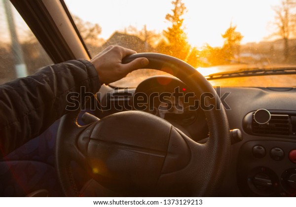 driving a car on a hot summer sunny day. hands of\
the driver behind the\
wheel.