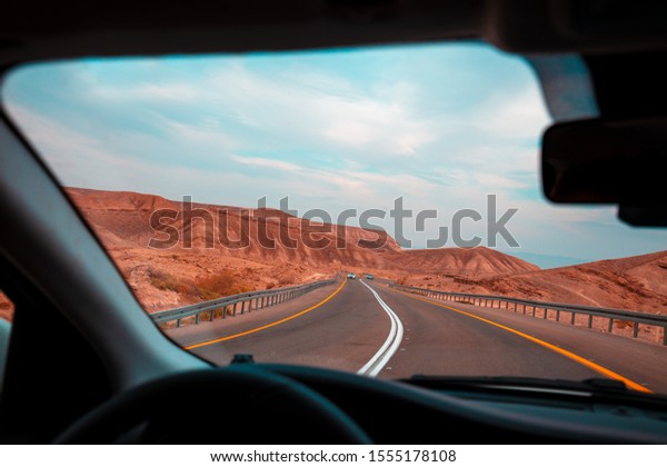 Driving a car on mountain Israel road. Desert\
landscape. Journey by car. View from car of mountain landscape in\
evening. Israel