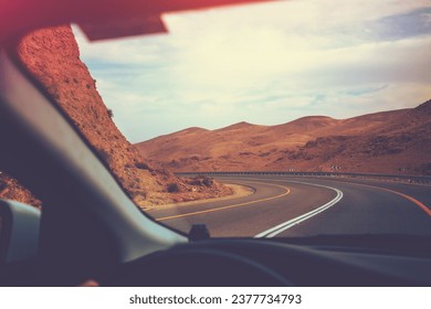 Driving a car on mountain road in desert. View of sandstone mountains through windscreen. Israel - Powered by Shutterstock