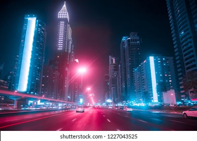 Driving a car on Sheikh Zayed Rd in Dubai at night, United Arab Emirates. Blurred motion. Duotone retro wave neon noir lights color toned
