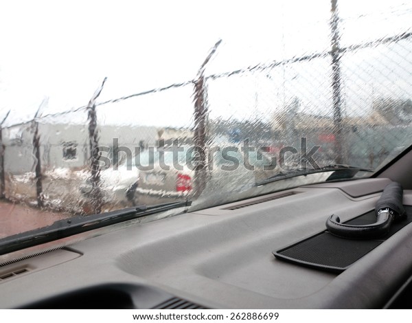 Driving a car in the rain front window with\
windscreen wiper