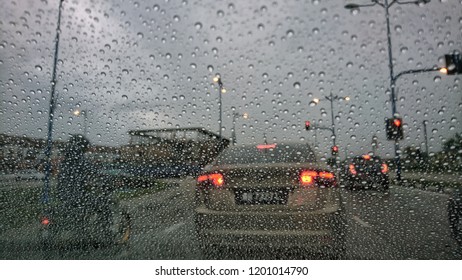 Driving car in the rain on wet road. Rainy weather through the car window. Rain through wind-screen of moving car. View through the car window in the rain. Selective focus. 