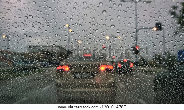 Driving car in the rain on
wet road. Rainy weather through the car window. Rain through
wind-screen of moving car. View through the car window in the rain.
Selective focus. 