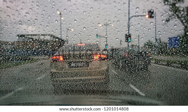Driving car in the rain on\
wet road. Rainy weather through the car window. Rain through\
wind-screen of moving car. View through the car window in the rain.\
Selective focus. 
