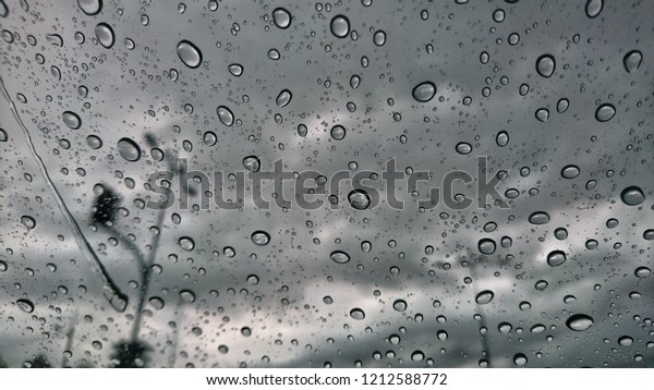 Driving car in the rain on wet road. Rainy\
weather through the car window. Rain through wind-screen of moving\
car. View through the car window in the\
rain.
