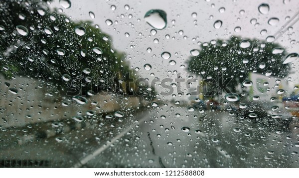 Driving car in the rain on wet road. Rainy
weather through the car window. Rain through wind-screen of moving
car. View through the car window in the
rain.