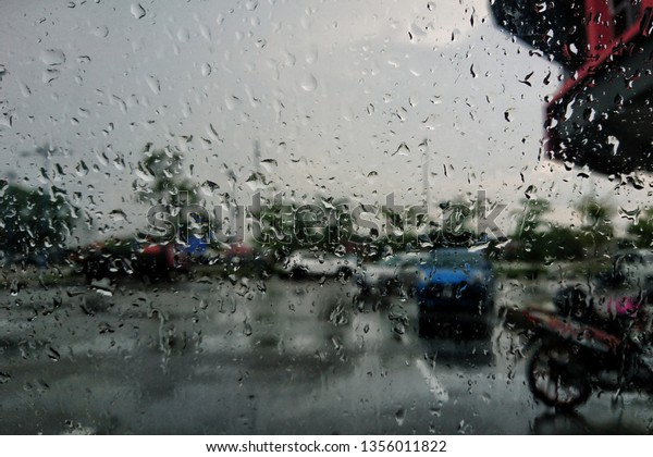 Driving car in the rain on wet road. Rainy\
weather through the car window. Rain through wind-screen of moving\
car. View through the car window in the\
rain.