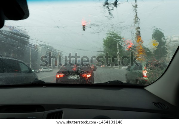 Driving car in the rain on wet road. Car windshield\
wipers on in the rain.