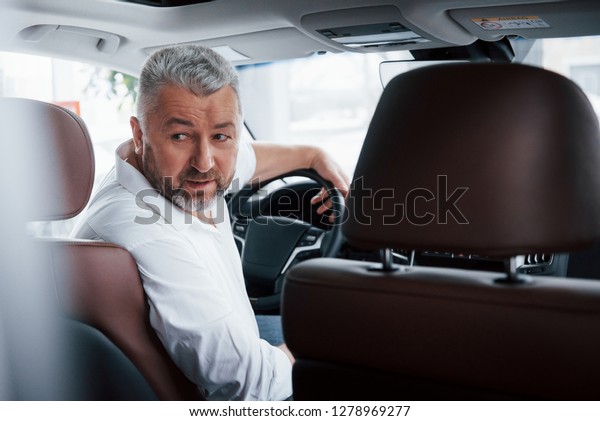 Driving a car in reverse gear. Looking\
behind. Man in his brand new\
automobile.