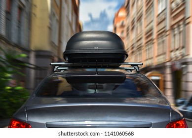 driving car with trunk on roof by city street