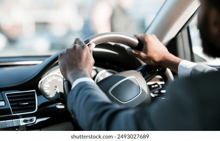 Driving Car. Unrecognizable Black Driver Holding Steering Wheel Sitting In New Auto. Selective Focus, Cropped - Powered by Shutterstock