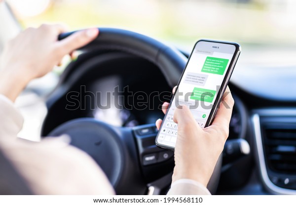 Driving car and using phone. Distracted driver\
texting with mobile cellphone. Irresponsible woman checking sms\
message with smartphone in traffic. Auto accident concept. Holding\
smart device in hand.