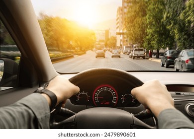 Driving car, view from driver's seat. Man holding hands on steering wheel, closeup