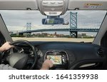 Driving a car while using the touch screen of a GPS navigation system towards Benjamin Franklin Bridge, Philadelphia, Pennsylvania, USA