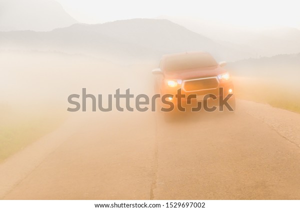 Driving cars in the fog mountain wuth headlight\
beams in dense mist.