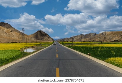 Driving down an empty road with a view of mountains in the distance and cloudy sky through a front car windshield. 