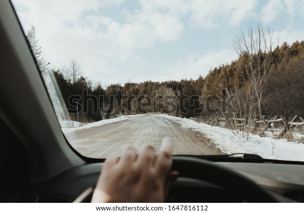 Driving down the road in winter. Snow\
on the road. Driving holding steering wheel point of\
view