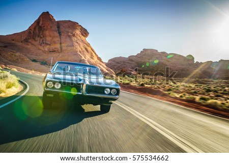 driving fast through desert in vintage hot rod car with lens flare and motion blur
