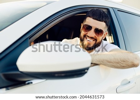 Driving his car, Handsome young man smiling while driving a car, Man in the driver's seat of a car