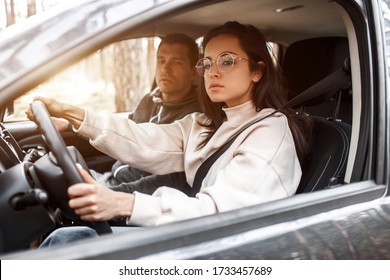 Driving instruction. A young woman learns to drive a car for the first time. Her instructor or boyfriend helps her and teaches her - Shutterstock ID 1733457689