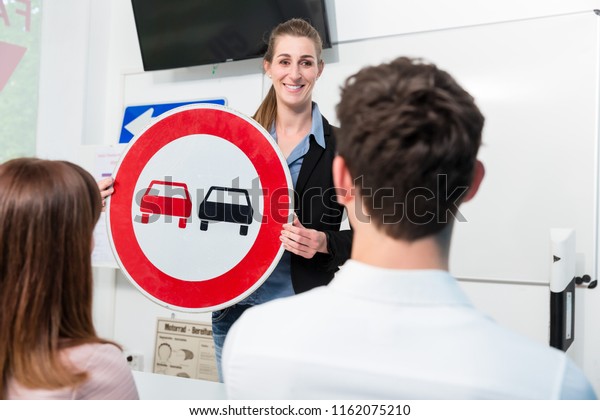 driving-instructor-explaining-meaning-street-sign-stock-photo