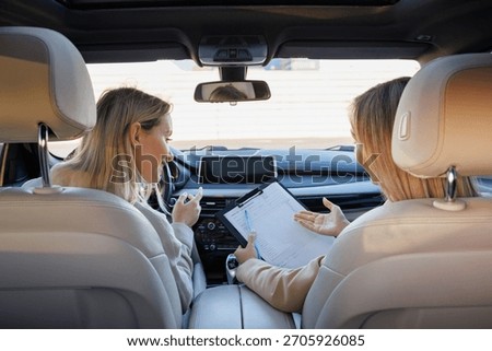 Driving Instructor Explaining Test Form to Learner Driver in Car Interior
