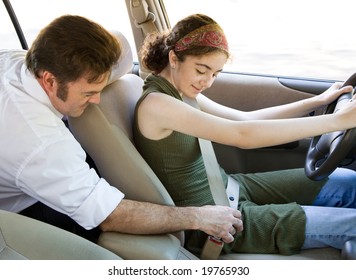 Driving Instructor Or Father Encouraging A Teen Driver To Use Her Seatbelt.